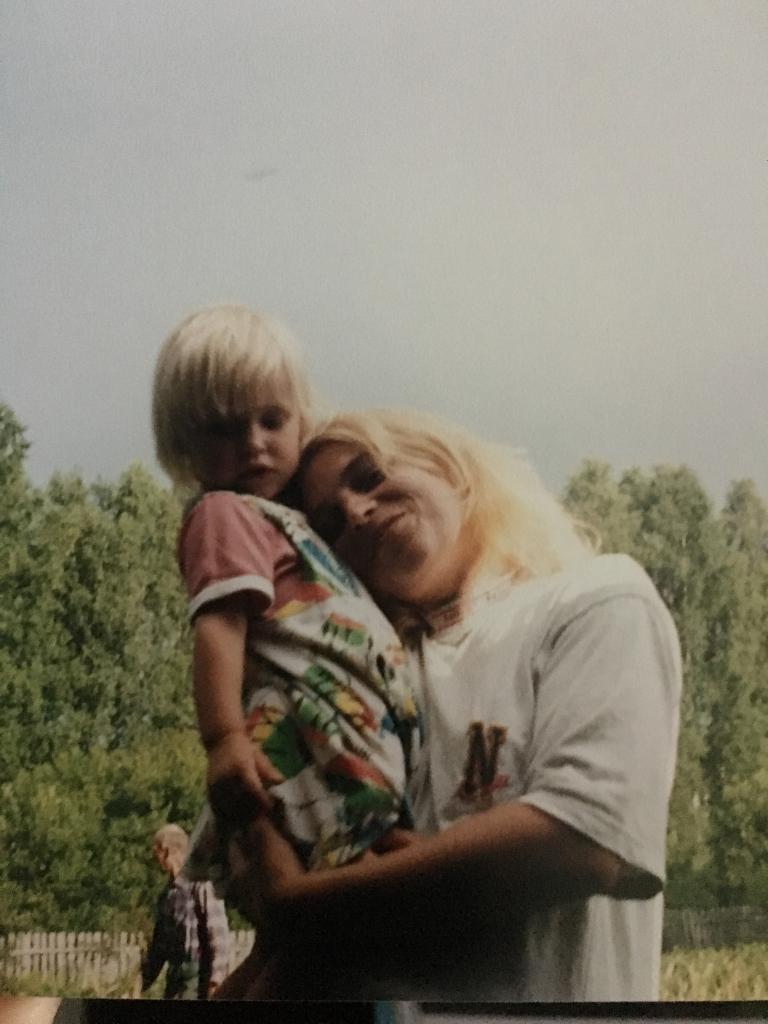 Mamma stāv un tur rokās bērnu, cenšas pieglausties